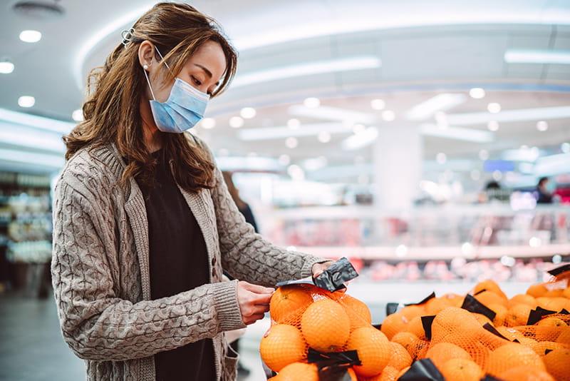 Woman grocery shopping in mask