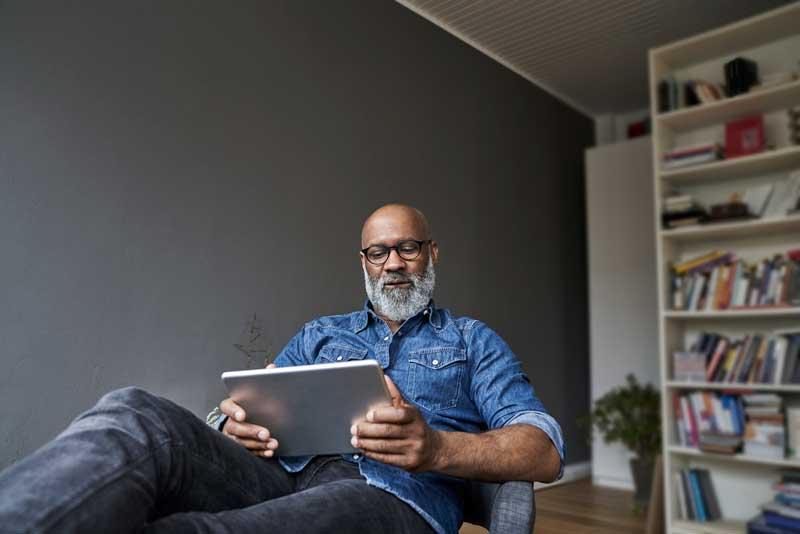 一个男人在家里用他的平板电脑放松